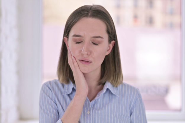 common dental problems (7) woman holding her jaw because of Common Dental Problems