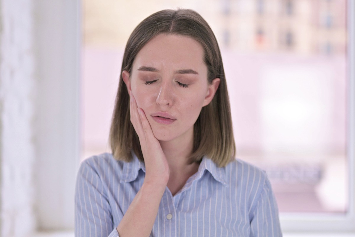 common dental problems (7) woman holding her jaw because of Common Dental Problems