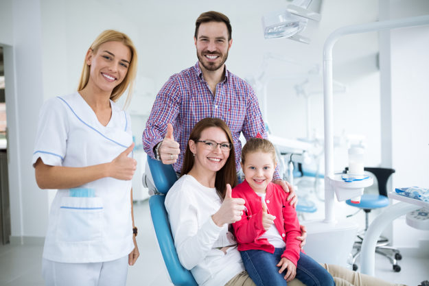 a family smiling with their family dentist