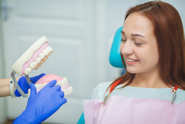 4 Benefits of Dental Implants (3) dentist explains a dental implant to a patient